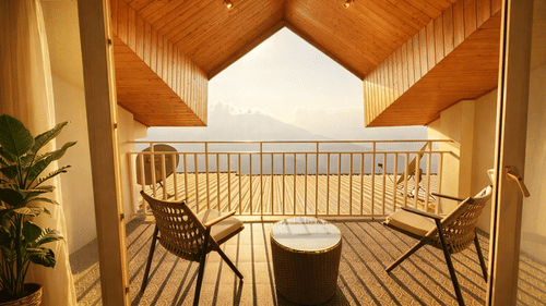 Room with balcony at Pride Premier Darjeeling featuring two chairs and a centre table facing towards the mountain view.
