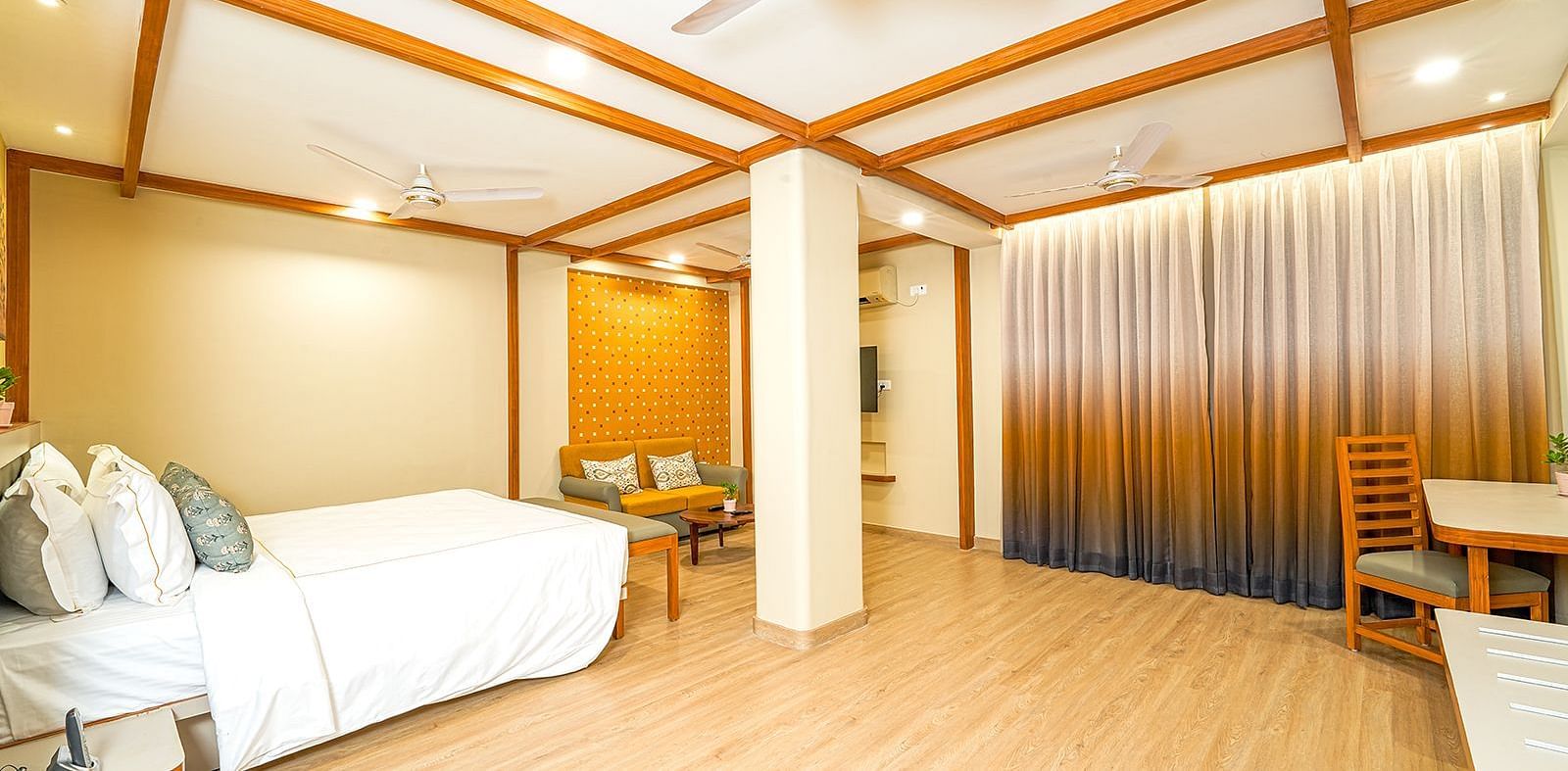 Spacious suite at Vasundhara Villa, Ramoji Film City featuring a cozy bed, stylish wooden interiors, and ample seating area for a relaxing stay.