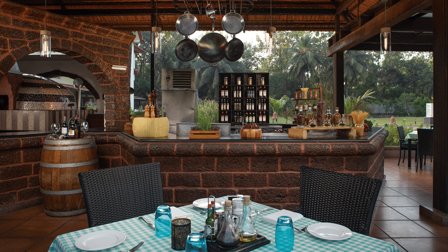 Outdoor dining table set with checkered linen near a brick counter at Kenilworth Resort & Spa, Goa.