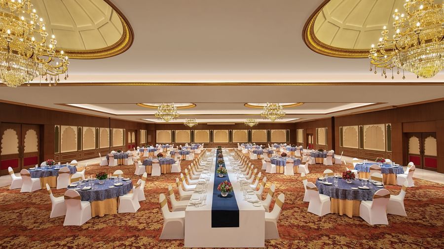 An image of a cosy event hall in Mahabalipuram with long and round tables, chandeliers, and carpeted floors – Kaldan Samudra Palace, a Luxury Wedding Hall in ECR