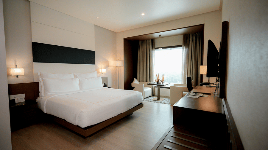 Spacious hotel room with minimalist decor at Narayani Heights Hotel & Resorts, Ahmedabad.