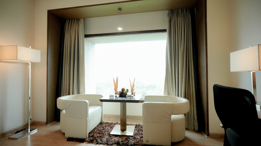 Plush seating area near window with table and armchairs – Narayani Heights Hotel & Resorts