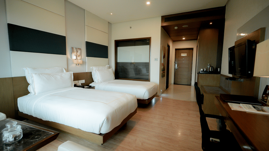 Spacious hotel room with plush twin beds and a work area – Narayani Heights Hotel & Resorts