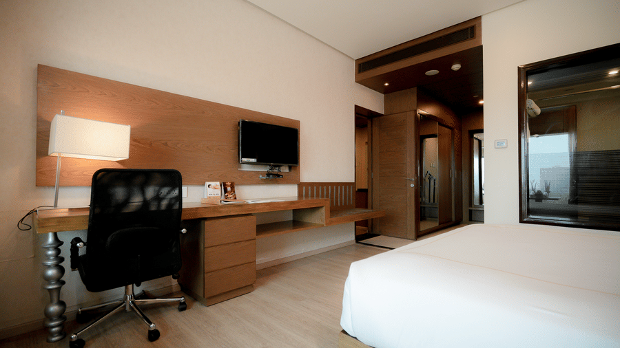 Modern room featuring a comfortable bed, work desk, and a flat-screen TV - Narayani Heights Hotel & Resorts