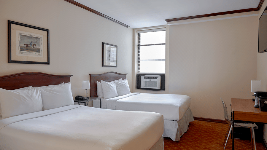 Room at Night Hotel Broadway showing two beds, desk area, framed art, and window.