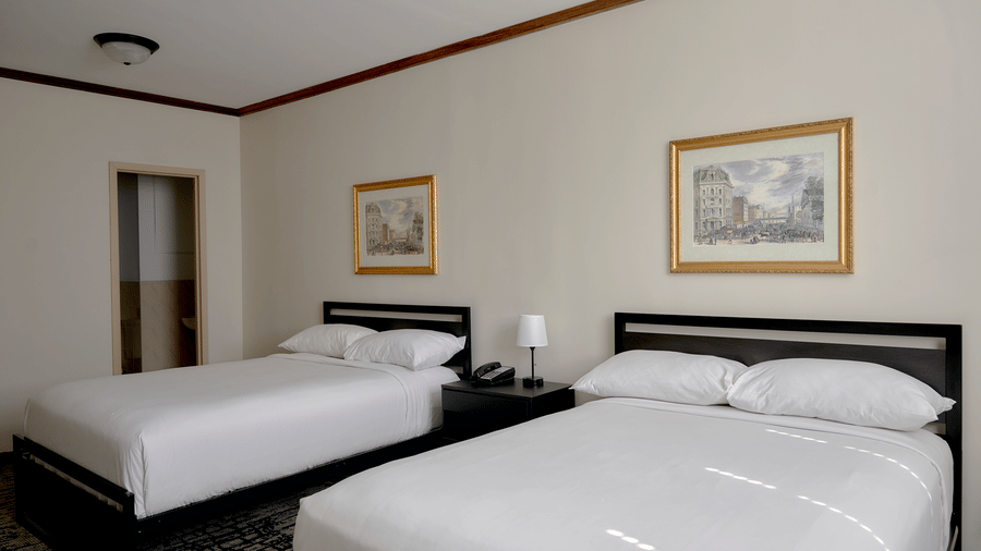 Spacious room at Night Hotel Broadway with two double beds, wall art, and bedside tables.