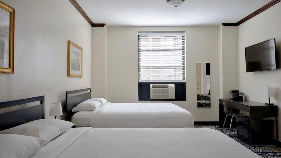 Room at Night Hotel Broadway with a large bed, armchair, TV, and window view.