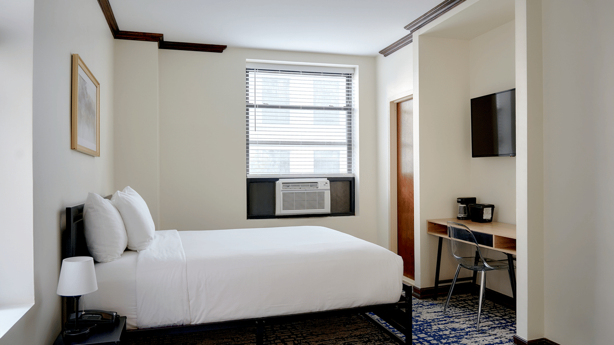 Compact room at Night Hotel Broadway with a double bed, desk, and wall-mounted TV.