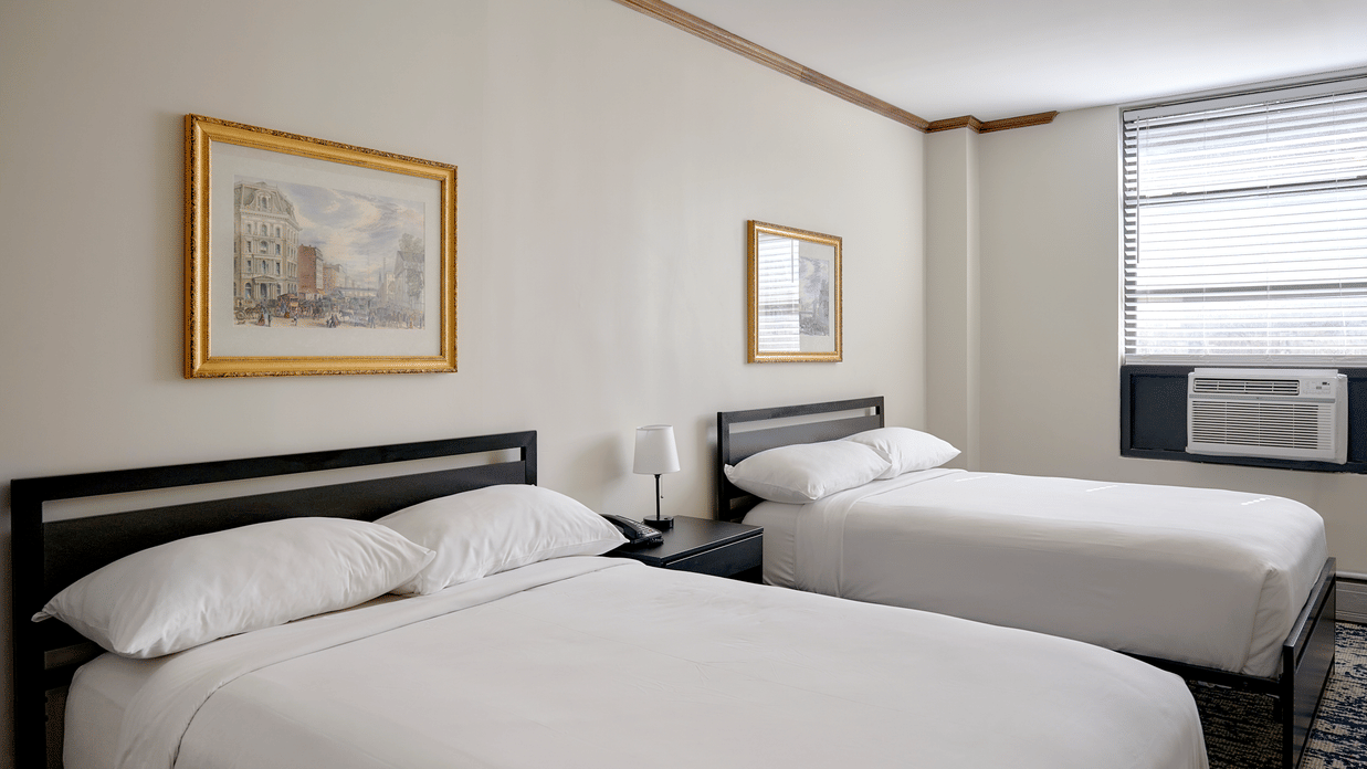 Night Hotel Broadway guest room featuring two double beds, framed artwork, and window.