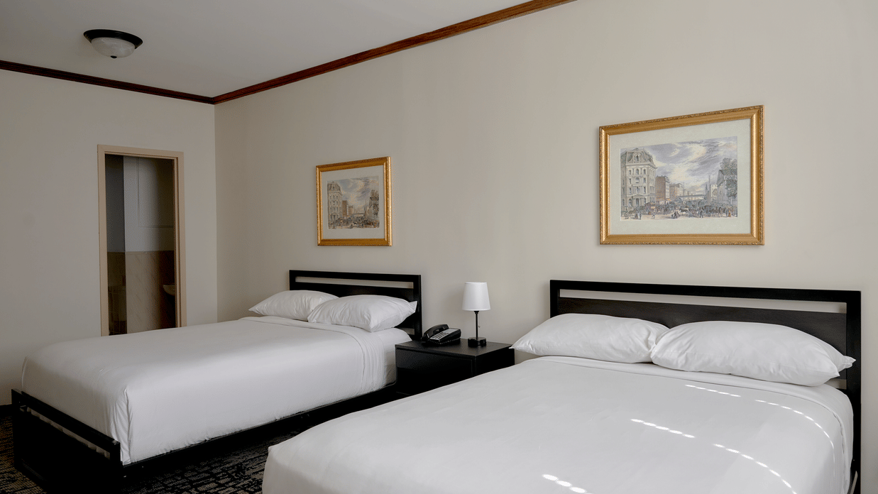 Spacious room at Night Hotel Broadway with two double beds, wall art, and bedside tables.