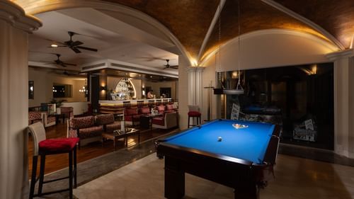 image of a dimly lit room featuring a blue coloured pool table in the middle
