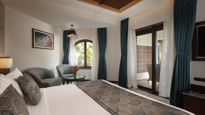 Junior Suites at Kenilworth Resort & Spa, Goa, featuring a plush bed and a seating space by the window, an ideal stay for guests visiting for a beachside wedding in Goa