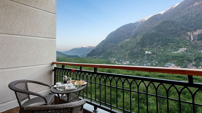 room in manali with balcony overlooking the lush greenery and mountains