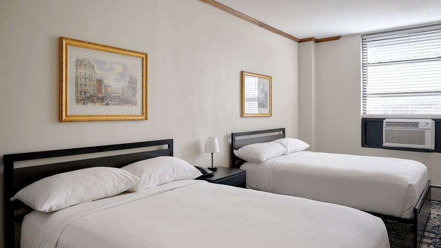 Night Hotel Broadway guest room featuring two double beds, framed artwork, and window.