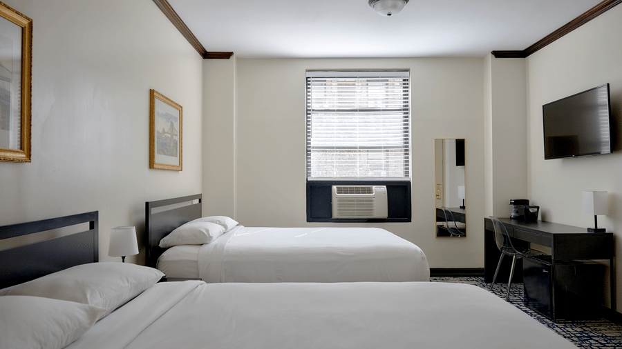 Room at Night Hotel Broadway with a large bed, armchair, TV, and window view.