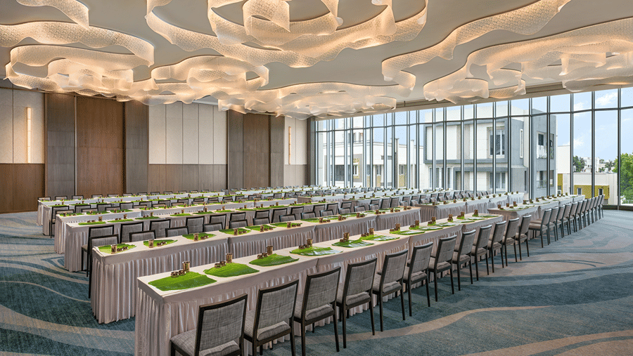 Long parallel tables with banana leaves arranged neatly inside the bright event hall of Ballroom 2 with decorative ceiling art at The Residency Towers Chennai.