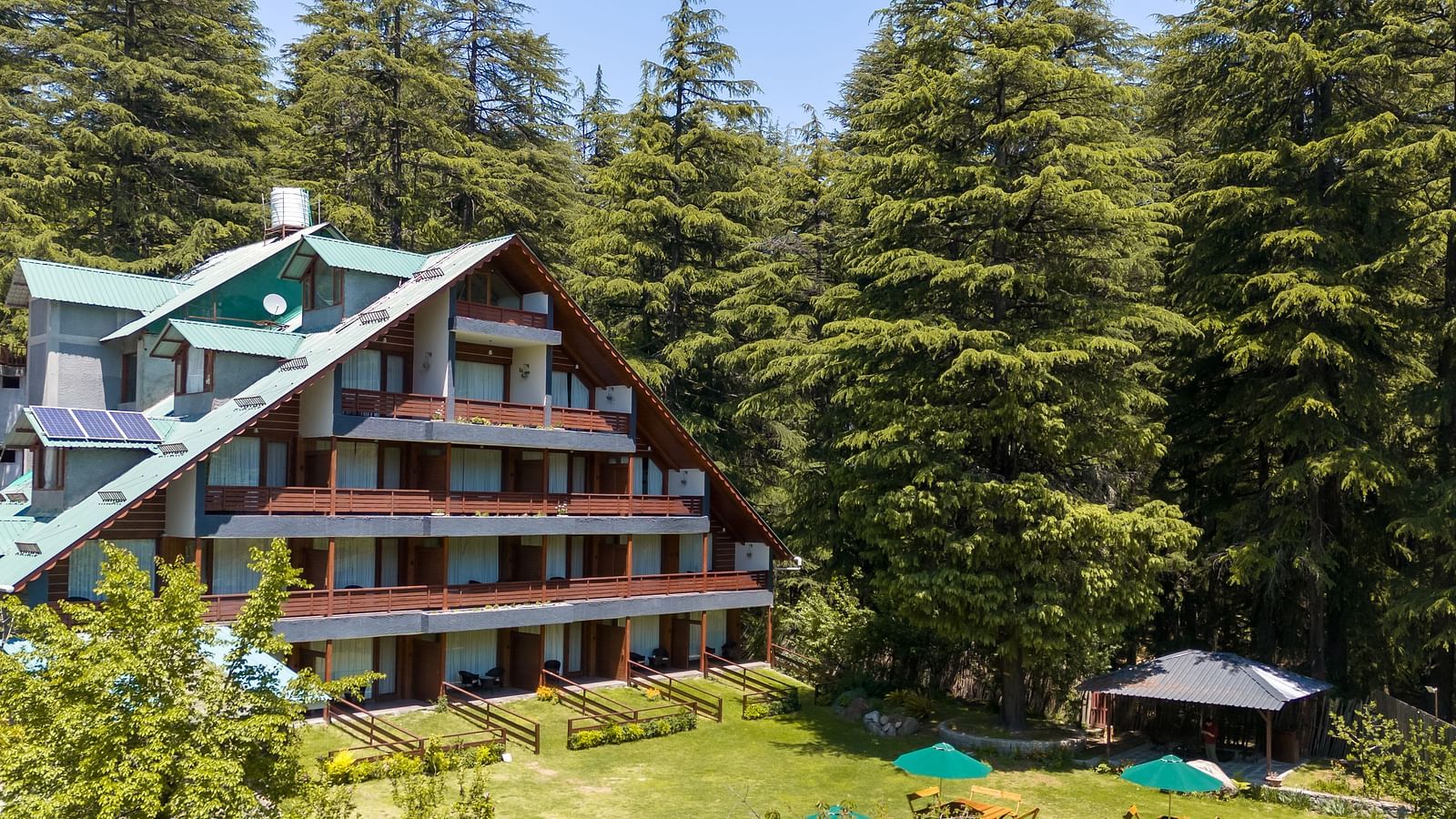 An image of a four storey attic style building set amidst the tall trees - Bedzzz Xclusiv Baikunth, Manali