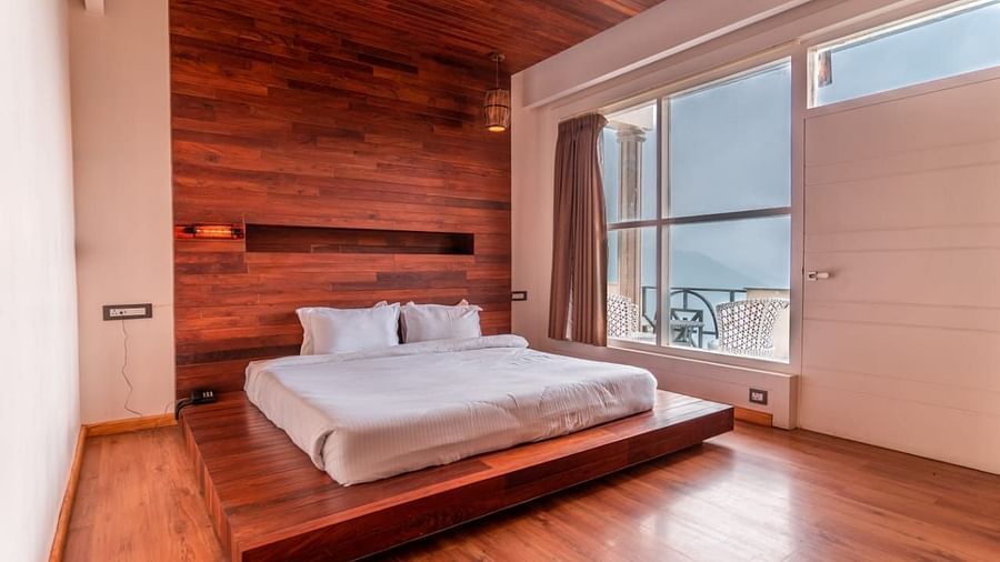 A bedroom with a raised platform bed, wooden walls, and a large window, emphasizing the unique architectural elements.