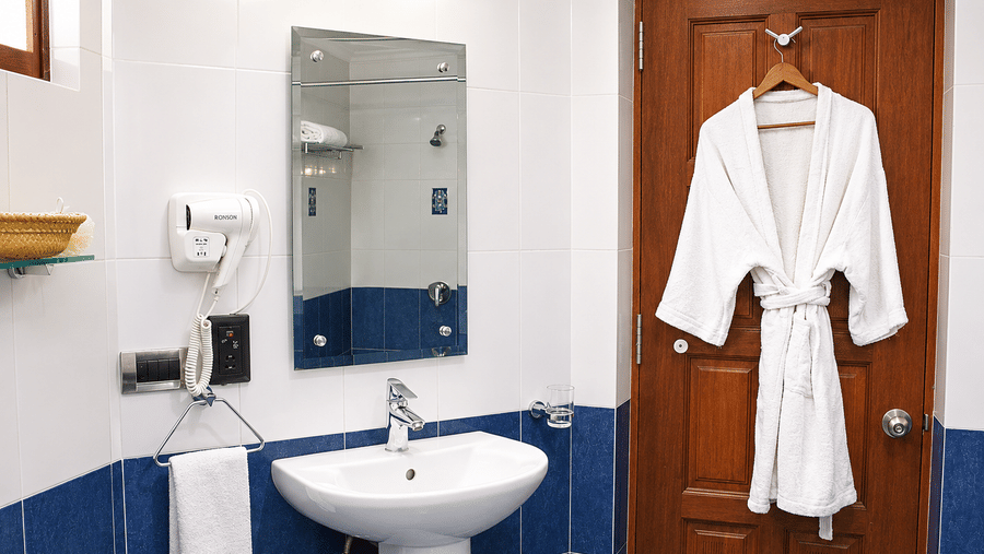 Wash Room 4 with a pedestal sink, blue tiled walls, and a plush bathrobe at Chariot Beach Resorts, offering a comfortable guest experience.