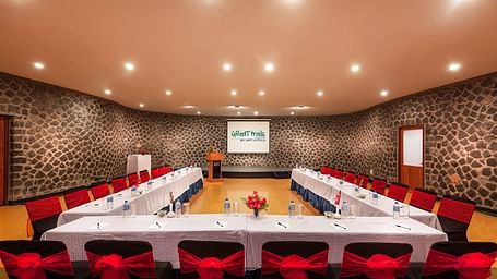 An image of a conference hall with seating arrangement and bright lighting - Great Trails Yercaud by GRT Hotels