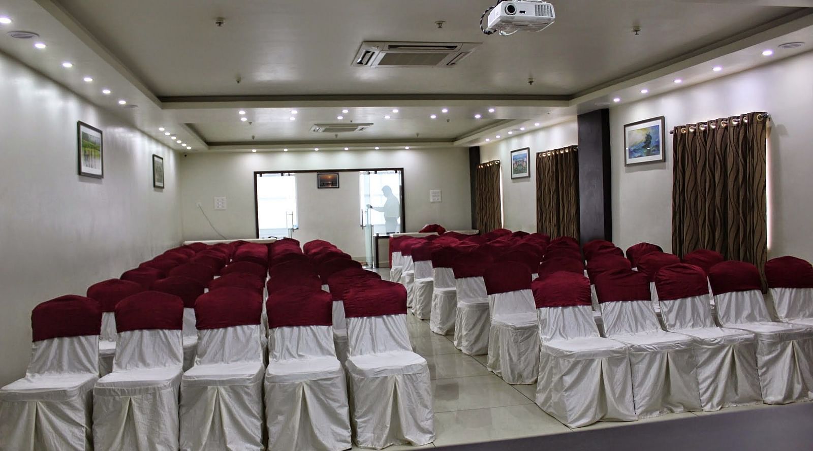 Jyothi hall with seats arranged and lights on the ceiling at Hotel Green Apple