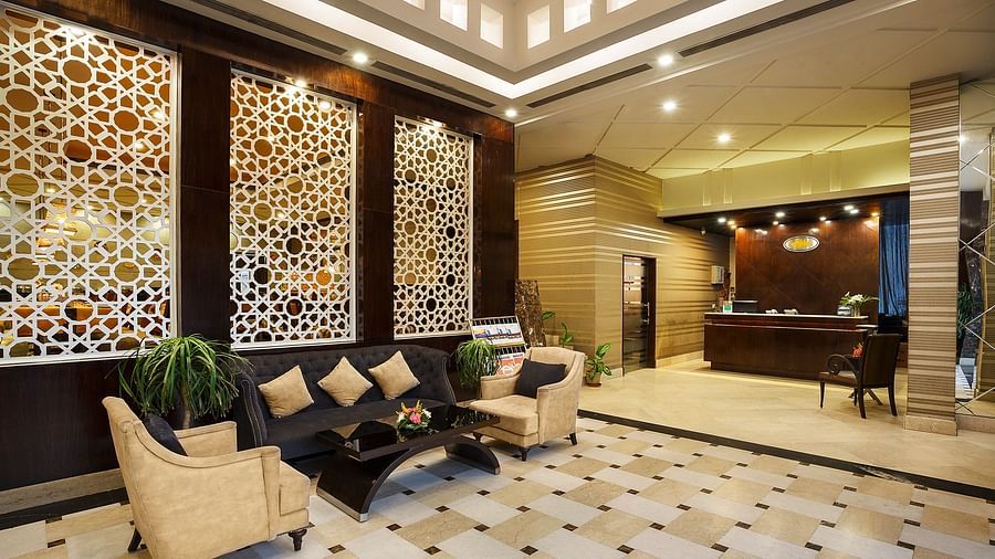 A sophisticated hotel lobby featuring a geometric patterned boards, plush seating, and a reception desk - The Manor, Bareilly