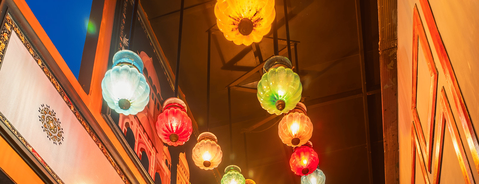 A staircase with colourful hanging lanterns and decorative walls on either side at Infiniti Hotel, Indore.