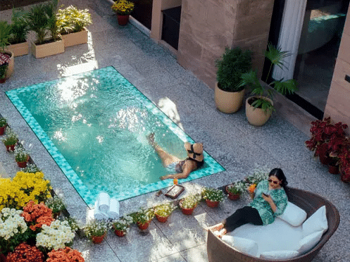 Outdoor hot tub surrounded by plants and seating, placed on a private stone patio with flower pots at Karma Chalets.