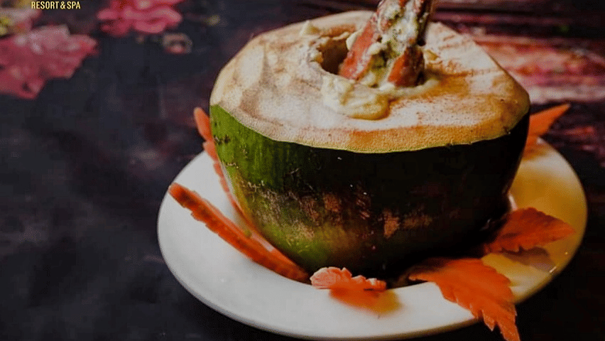 Traditional Daab Chingri served inside a tender coconut shell, showcasing Bengali-style prawn curry presentation.