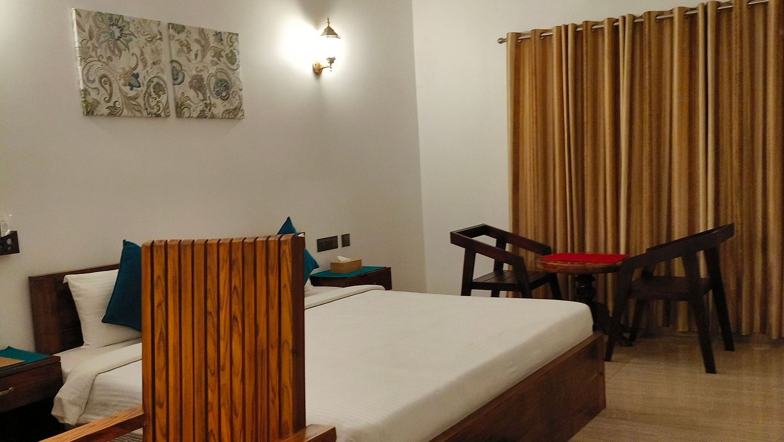 Side view of a chair with a desk and a double bed behind it in 102 room at Ananda Holiday Home, Wayanad 8