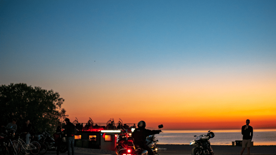 a man on a motorcycle looking at the sunset