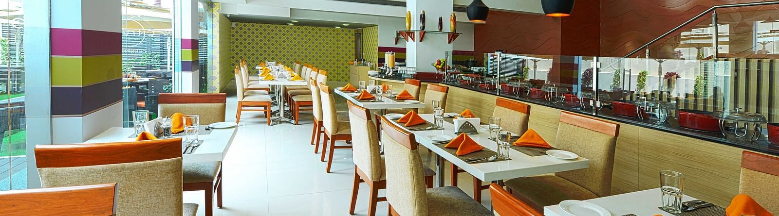 Coffee Shop at The Cunningham Hotel featuring modern decor, warm lighting, neatly arranged tables, and large windows overlooking the outdoors