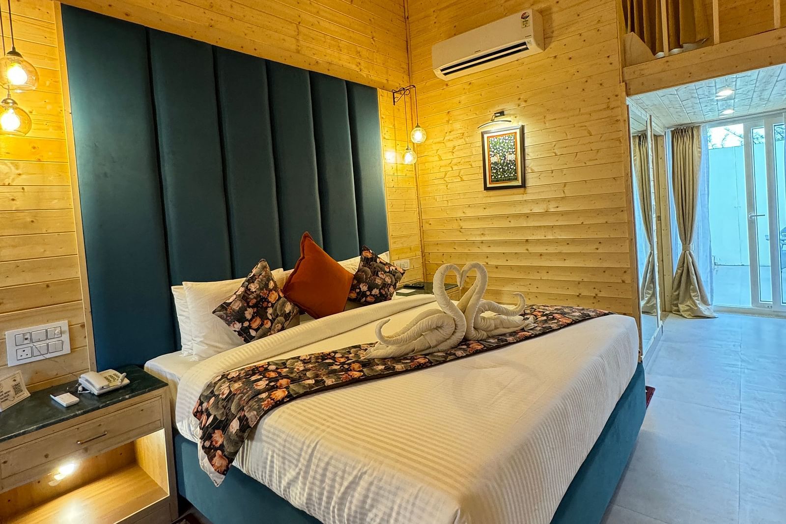 An interior shot of a hotel room with wooden paneled walls. The room has a bed with a white comforter and a decorative runner - Bamboo Saa Mulberry Resort, Pushkar