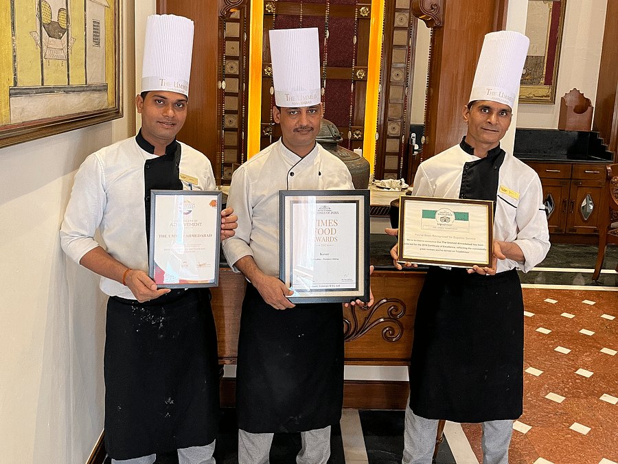Chefs at Kesar proudly standing together with a decorative frame at the Ummed Ahmedabad.