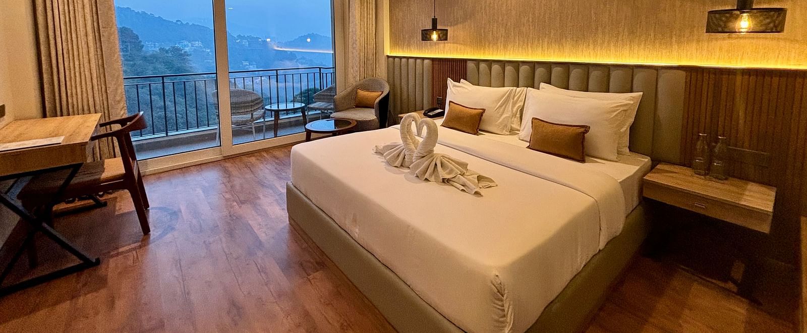 Elegant bedroom with large windows, wooden accents, and a scenic balcony view – ARNISA Boutique Hotel