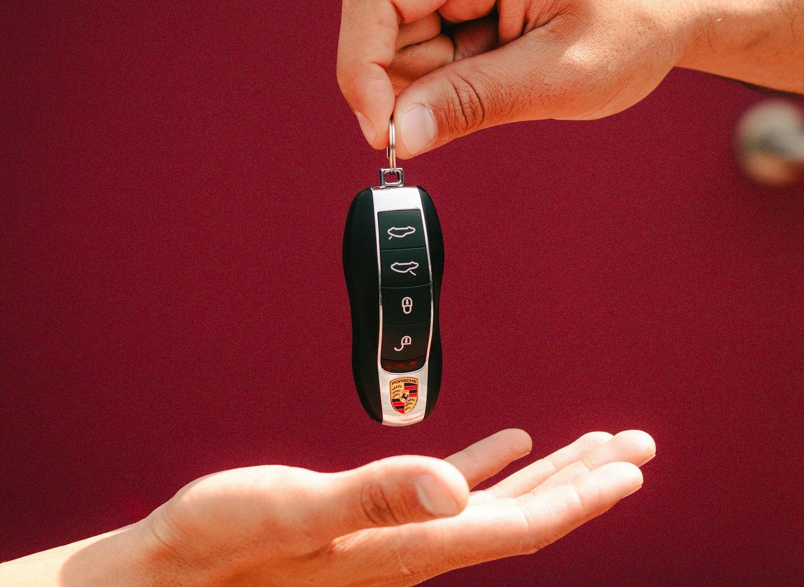 Two hands are exchanging a set of car keys.