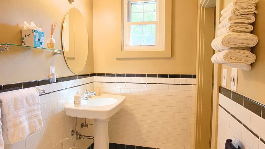 a bathroom with a commode and a wash basin alon with a wall mounted rack with folded towels - Historic Tapoco Lodge