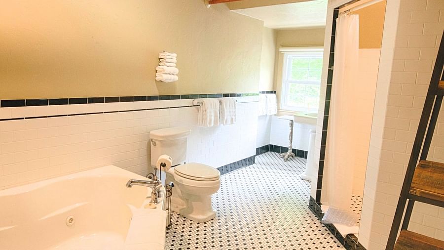 a wide angle view of the bathroom with black and white tiles along with a bathtub and a shower cubical - Historic Tapoco Lodge