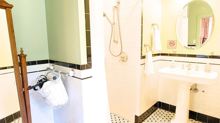 a bathroom with black and white patterned tiles along with a wash basin at the far end of the bathroom - Historic Tapoco Lodge