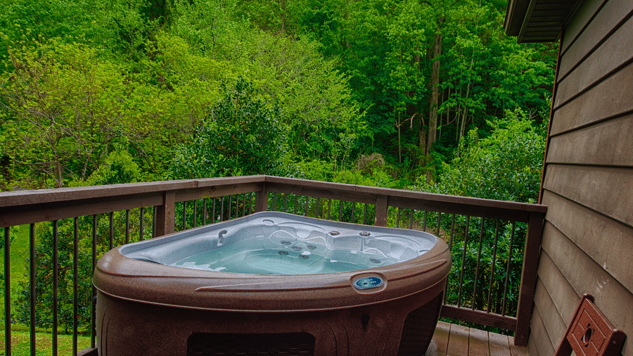 a private hot tub on a wooden porch surrounded by lush green views of the forests - Historic Tapoco Lodge