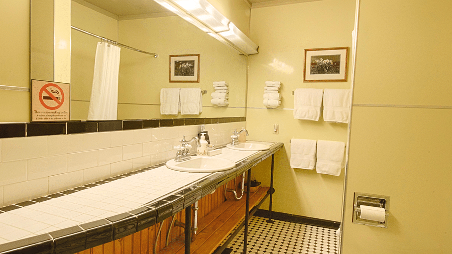 a bathroom featuring a wide mirror and a wash basinfull view image of a bedroom with wooden interiors featuring two beds - Historic Tapoco Lodge