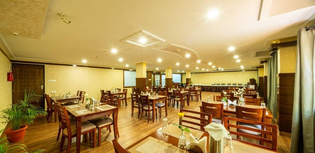 A brightly lit dining room with wooden tables and chairs offers a welcoming atmosphere for meals at Lords Midtown Suites.