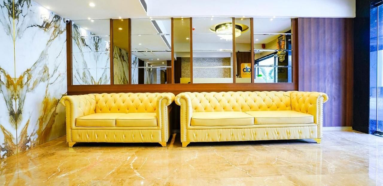 Hotel lobby seating area with two yellow sofas and marble floor - Shyanu Lords Eco Inn Airoli