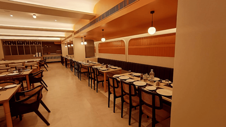 The orange accented dining set-up where dining tables are placed parallel to each other with warm overhead lighting in the best hotel in Belgaum, Lords Eco Inn, Belagavi.