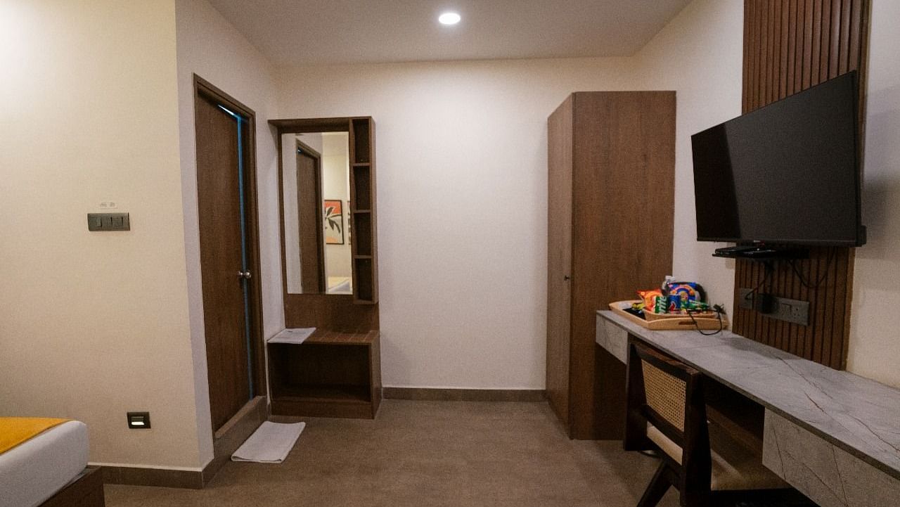 A spacious room with a wide-angle view, showing the work desk, TV, and ample storage cabinets at Hotel Kyzen Smartstays – Smart, Reliable, Kyzen