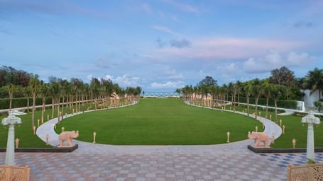 An outdoor lawn in Mahabalipuram surrounded by lush greenery and offering views of the sea – Kaldan Samudra Palace, one of the premier Outdoor Lawn Wedding Venues in ECR