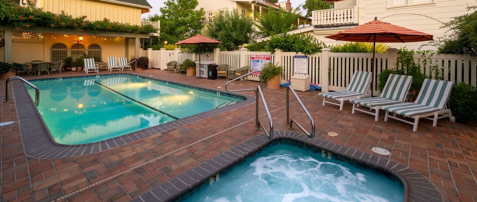 A refreshing outdoor swimming pool and a relaxing hot tub surrounded by comfortable lounge chairs at The Tallman Hotel.