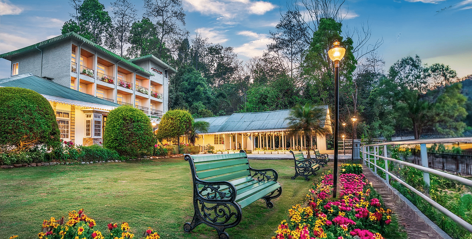 Facade of Summit Barsana Resort & Spa, Kalimpong with a bench in front and flowers around it.