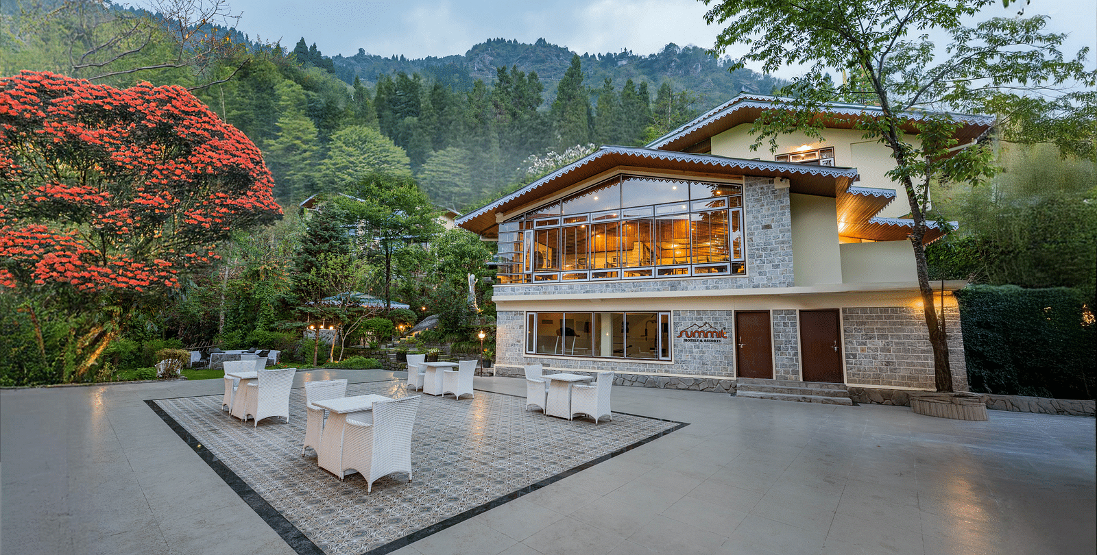 Facade of Summit Norling Resort & Spa, Gangtok with trees on the side and mountains in the background.