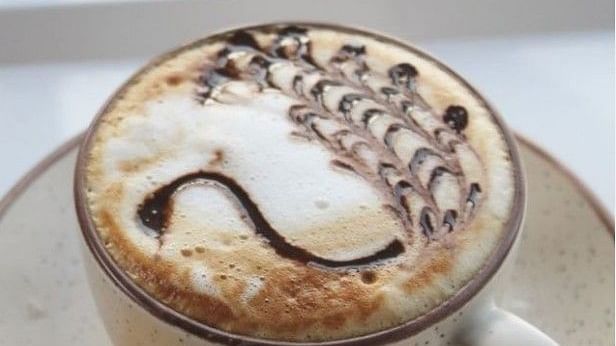 A cup of coffee with a design on and a cookie beside it- Arcadia Heritage Resort, Darjeeling